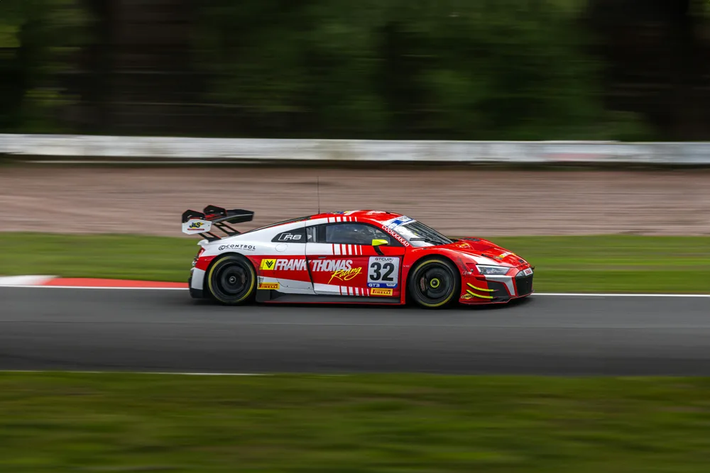 Une Audi R8 de course rouge et blanche sur la piste d’Oulton Park